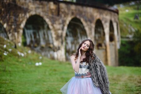 the bride walks under a bridge in a fur Cape in the Carpathiansの写真素材