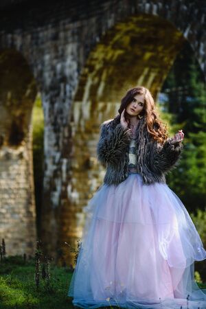the bride walks under a bridge in a fur Cape in the Carpathiansの写真素材