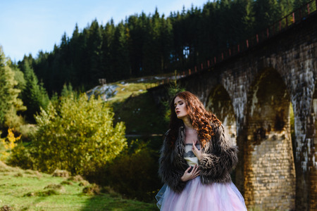 the bride walks under a bridge in a fur Cape in the Carpathiansの写真素材