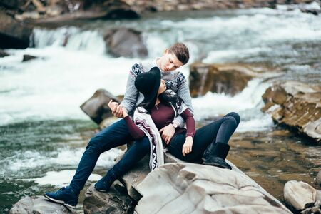 guy and girl in warm sweaters by a mountain river, romancingの写真素材
