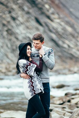 guy and girl in warm sweaters by a mountain river, love storyの写真素材