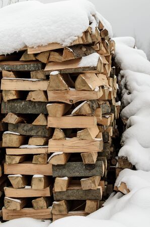 firewood in the snow, chopped singe harvested for fireplaceの写真素材