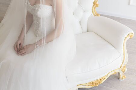 the bride sits on a vintage white chairの写真素材