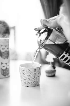 the girl pours a ?up of hot tea from the kettleの写真素材
