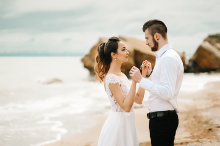 young couple groom with the bride on a sandy beach at a wedding walkの写真素材