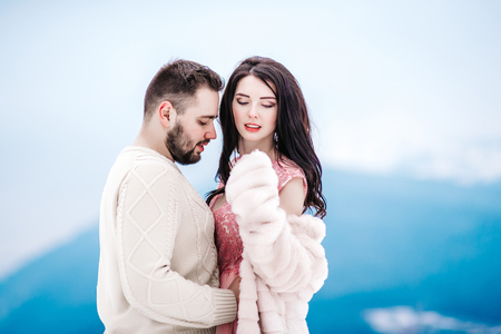 a bride in a fur coat with a fiance among the Carpathian mountainsの写真素材
