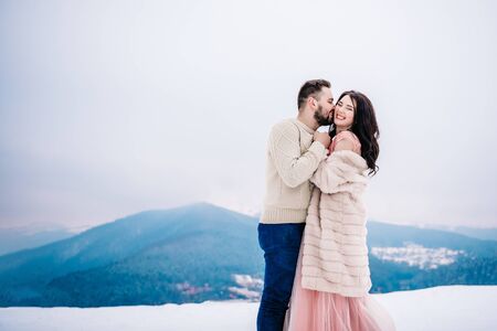 A bride in a fur coat with a groom among the Carpathian mountainsの写真素材