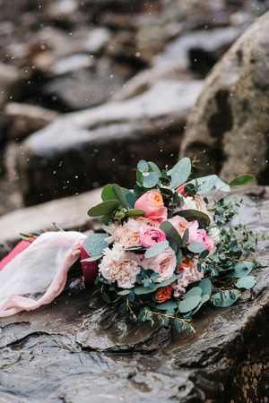 Wedding bouquet of peonies with ribbons on stone, close-up, it's snowingの写真素材