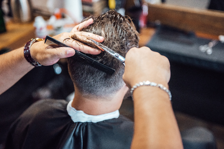 the master in the barbershop shaves and cuts the man in front of the mirrorの写真素材