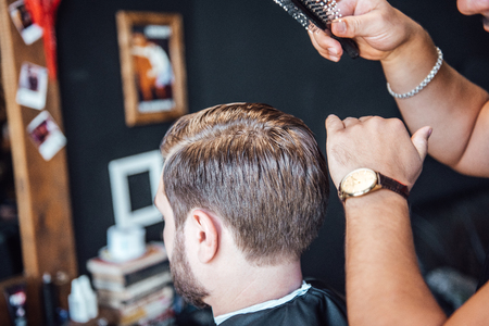 the master in the barbershop shaves and cuts the man in front of the mirrorの写真素材