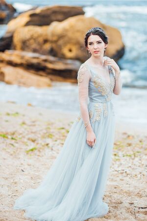 bride in a blue light dress walking along the oceanの写真素材