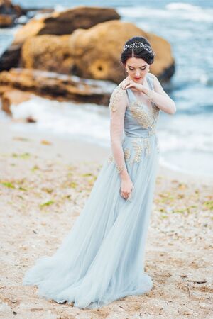 bride in a blue light dress walking along the oceanの写真素材
