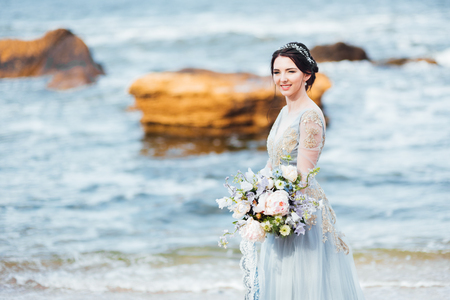 bride with a bouquet of flowers on the beach near the waterの写真素材