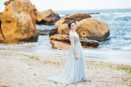 bride in a blue light dress walking along the oceanの写真素材