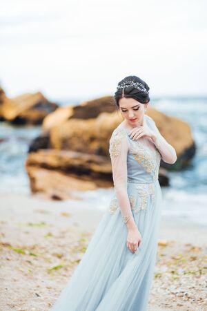 bride in a blue light dress walking along the oceanの写真素材