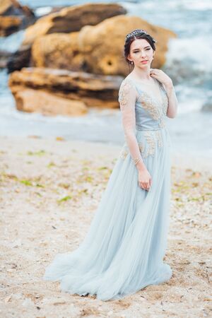 bride in a blue light dress walking along the oceanの写真素材