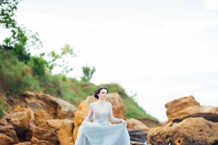 bride in a blue light dress walking along the oceanの写真素材