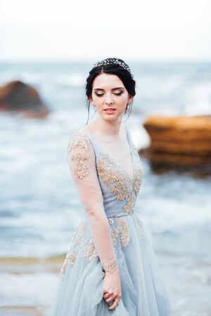 bride in a blue light dress walking along the oceanの写真素材