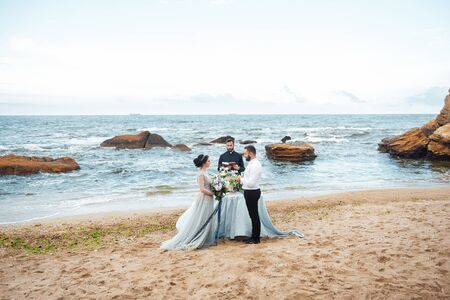 wedding couple on the ocean with a priestの写真素材