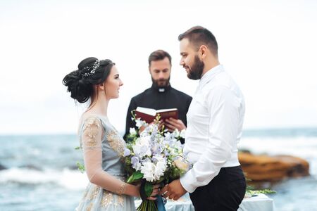 wedding couple on the ocean with a priestの写真素材