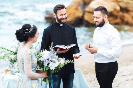 wedding couple on the ocean with a priestの写真素材