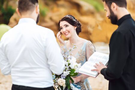 wedding couple on the ocean with a priestの写真素材