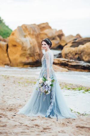 bride with a bouquet of flowers on the beach near the waterの写真素材