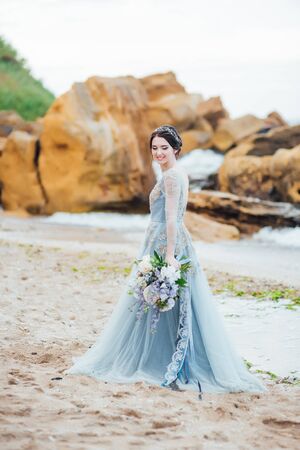 bride with a bouquet of flowers on the beach near the waterの写真素材