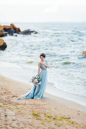 bride with a bouquet of flowers on the beach near the waterの写真素材