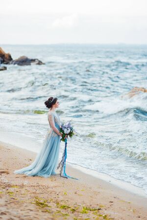 bride with a bouquet of flowers on the beach near the waterの写真素材