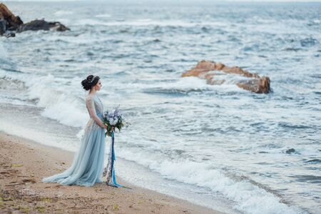 bride with a bouquet of flowers on the beach near the waterの写真素材