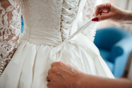 dress up the bride in a wedding dress with corset and lacingの写真素材