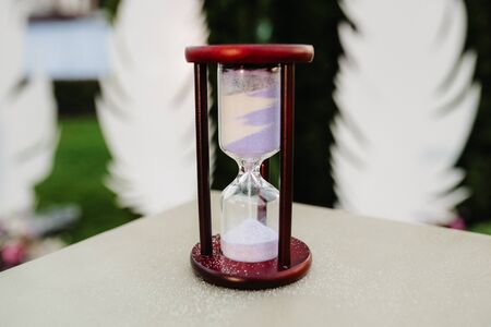 white sand hourglass in brown wood on tableの写真素材
