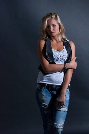 young, blonde girl in jeans clothes on a dark backgroundの写真素材