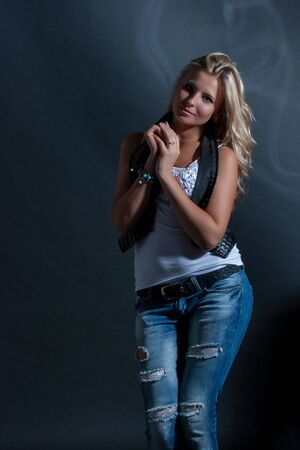young, blonde girl in jeans clothes on a dark backgroundの写真素材