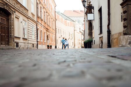 guy and a girl happily walk in the morning on the empty streets of old Europeの写真素材