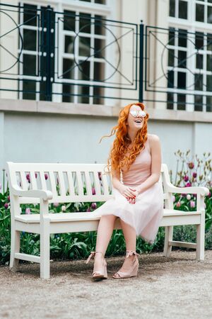 red-haired young girl walking in a park between trees and architectural objectsの写真素材