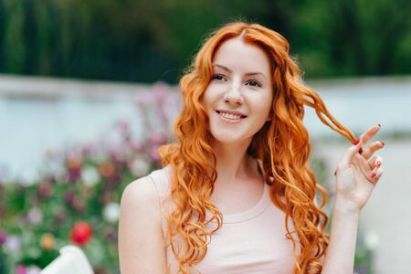 red-haired young girl walking in a park between trees and architectural objectsの写真素材
