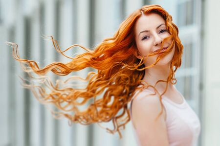 red-haired young girl walking in a park between trees and architectural objectsの写真素材