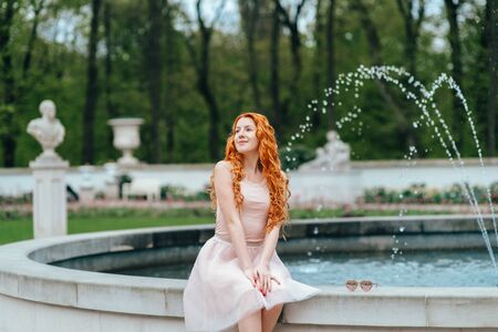 red-haired young girl walking in a park between trees and architectural objectsの写真素材