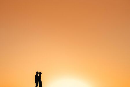 silhouettes of a happy young couple guy and girl on a background of orange sunset in the sand desertの写真素材