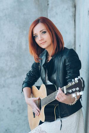 musician young girl with red hair with an acoustic guitarの写真素材