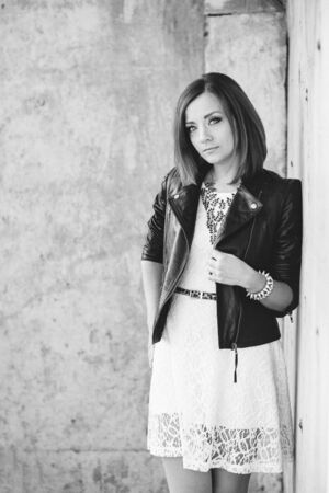 red-haired girl in a black jacket and blue glasses on a gray roadの写真素材