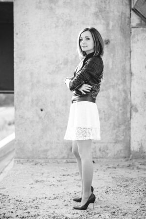 red-haired girl in a black jacket and blue glasses on a gray roadの写真素材