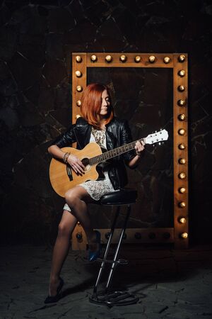 musician young girl with red hair with an acoustic guitarの写真素材