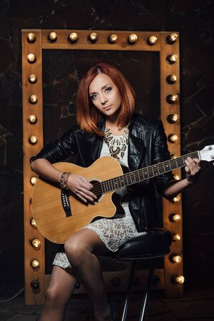 musician young girl with red hair with an acoustic guitarの写真素材