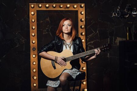 musician young girl with red hair with an acoustic guitarの写真素材