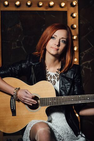 musician young girl with red hair with an acoustic guitarの写真素材