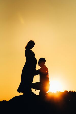silhouettes of a happy young happy family against an orange sunset in the desertの写真素材