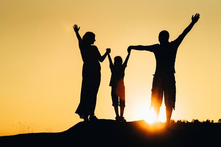 silhouettes of a happy young happy family against an orange sunset in the desertの写真素材